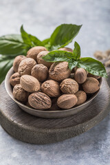 Whole nutmeg nuts in a bowl. Whole and halved nutmegs in a wooden bowl. Fragrant or true nutmegs,...