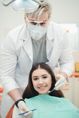 Photo of a man in a white coat and gloves checking a client for caries. girl at a dentist appointment
