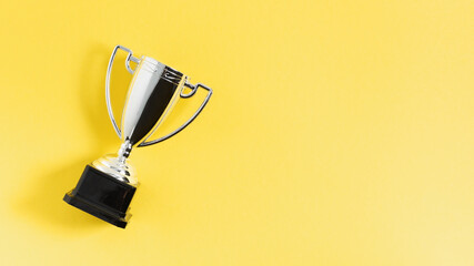 Winner or champion silver trophy cup on yellow background top view