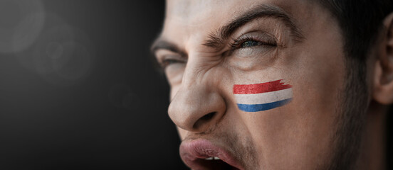 A screaming man with the image of the country's national flag on his face