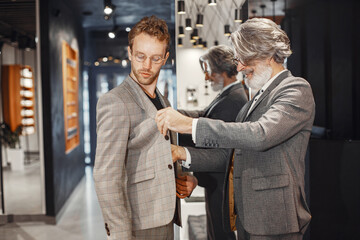 Portrait of a mature man. Assistant helps a costumer. Senior visiting a fashion boutique. Male buy...