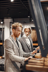 Portrait of a mature man. Assistant helps a costumer. Senior visiting a fashion boutique. Male buy a new exclusive costume.