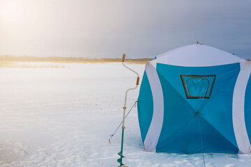 blue winter fisherman tent on the background of sunset near the lake