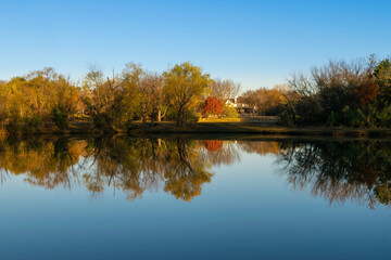 Autumn colors on a lake shore reflected on glassy smooth water