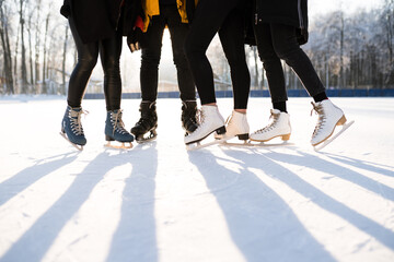 Obraz premium Legs in black jeans are wearing skates with a shadow on the snow