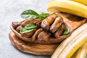 Sun dried bananas in wooden bowl on stone background. Copy space. Superfood, vegan, vegetarian concept.