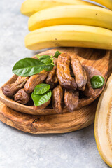 Sun dried bananas in wooden bowl on stone background. Copy space. Superfood, vegan, vegetarian concept.