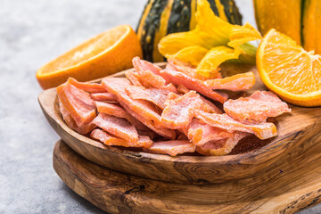 Dried pumpkin slices in plate on a dark stone background. Candied pumpkin.