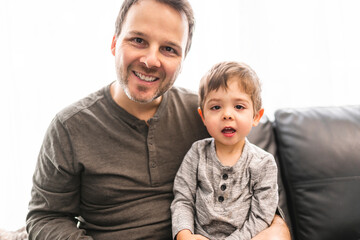 Portrait of smiling little boy with father on sofa