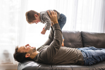 Portrait of little boy with father having fun on sofa
