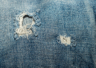 Blue denim with scuffs and holes close-up