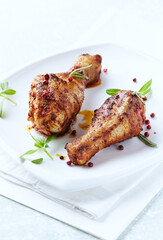 Baked chicken drumsticks with fresh herbs on bright background. Close up. 