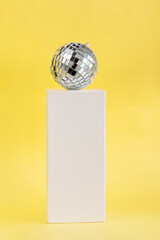 disco ball with sparkle on white pedestal against illuminating background
