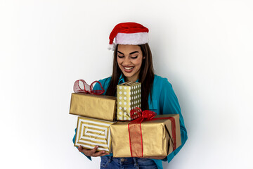 Portrait of a young woman wearing Santa hat holding christmas gifts smiling, looking happy and excited. Shot of beautiful Caucasian santa girl with a bunch of wrapped gift isolated on white background