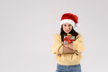 Christmas concept. Beautiful young woman holding christmas gift box with red bow wearing santa red hat. Smiling happy girl isolated on white background