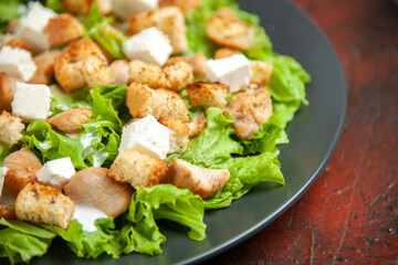 bottom close view caesar salad on oval plate on dark red background