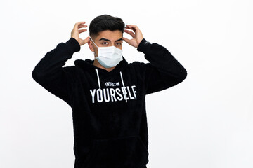 Young man wearing a black hoodie. He's wearing a medical mask. White background. Isolated image.