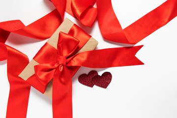 Single gift box with red ribbon, and two hearts end ebow on white background