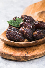 Beautiful juicy date with water drops. Fresh dates plucked from a tree in a plate. Dried dates on a wooden table, still life. Vegetarian food. Sweet snack. Large sweet dates close-up. Useful sweets fo