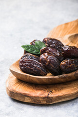 Beautiful juicy date with water drops. Fresh dates plucked from a tree in a plate. Dried dates on a wooden table, still life. Vegetarian food. Sweet snack. Large sweet dates close-up. Useful sweets fo