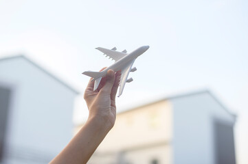 Woman hand is holding Airplane model against sunset , Holiday travel , business conservation transportation concept.
