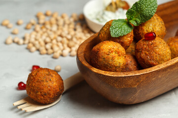 A vegetarian dish,falafel, fried chickpea balls in a small wooden bowl. Close-up with space.chickpea seeds in the background