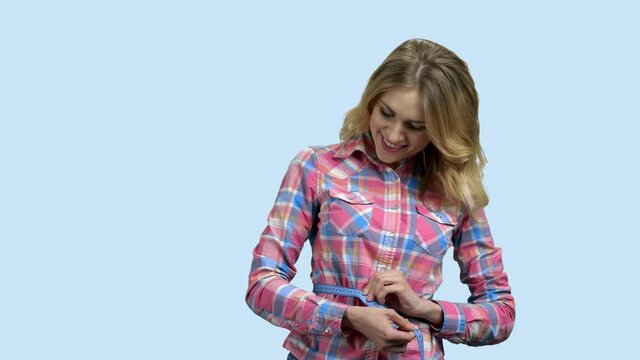 Slim woman with measuring tape on color background. Young happy woman measuring her waist with tape measure. Weight loss programs.