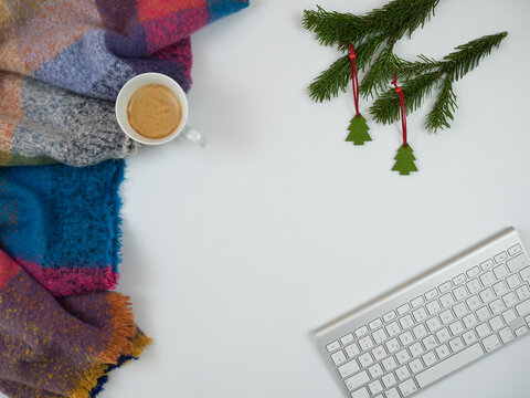 Christmas composition. Scarf with cup of coffee, keyboard and fir tree branches on white background. Flat lay, top view.