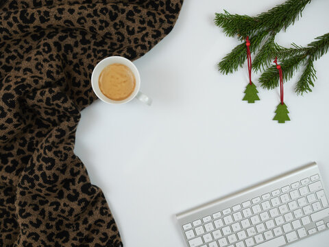 Christmas composition. Scarf with cup of coffee, keyboard and fir tree branches on white background. Flat lay, top view.