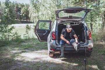 Fishing near the car in nature. Rest at nature. Man prepares fishing tackle near the car in nature.