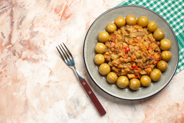 top view roasted eggplant salad and pickled plums on plate on turquoise white checkered napkin fork on nude background free place