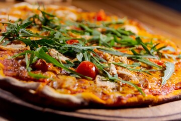pizza with arugula, meat and tomatoes on a wood plate for restaurant menu