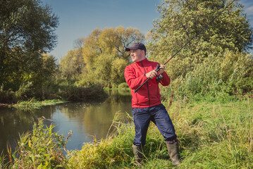 Fishermen fishing with a spinning rod from the shore on a sunny day. Fishing on a sunny day. Man on the river bank throws a spinning rod.