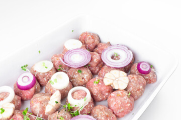 raw meat balls with vegetables and microgreens isolated on white