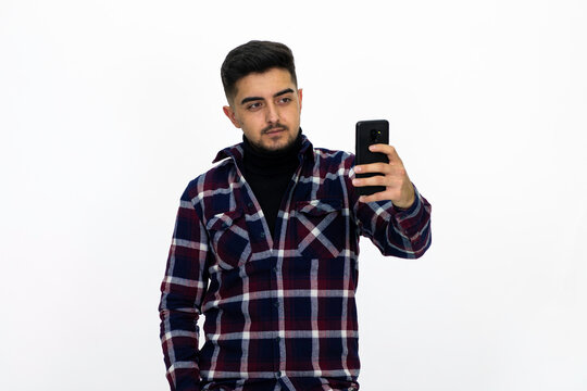 Young man wearing a dark striped shirt.  He has a phone.He has a dirty beard White background. Isolated image. 