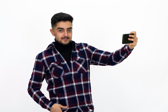 Young man wearing a dark striped shirt.  He has a phone.He has a dirty beard White background. Isolated image. 