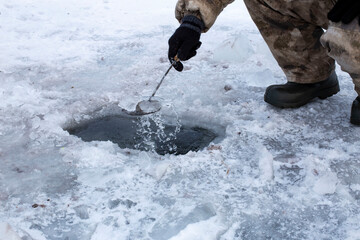 a poacher trying to catch fish using a net on the first ice of a frozen lake, the foreground and background are blurred