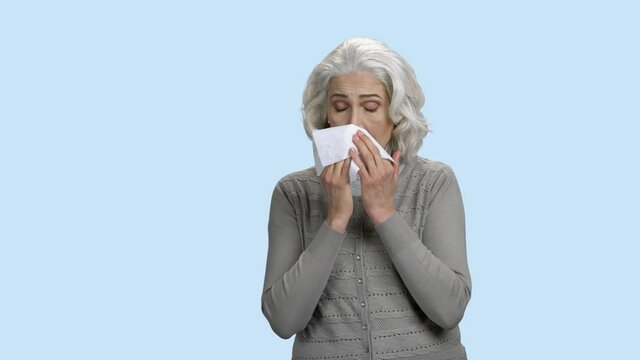 Mature woman sneezing. Sick senior woman catch a cold. Grippe or influenza concept.