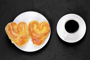 Pastry on a white plate and cup of coffee on a black background. Homemade cake. Fresh baked cake. Breakfast.