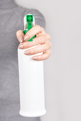 Hand with spray bottle on grey background.