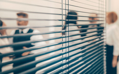 through the blinds. company employees in the workplace in the office.