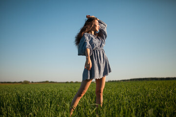 The girl walks in the field in summer.