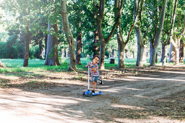 Smiling child on kick scooter in the countryside. Outdoor activity for children on safe rural...