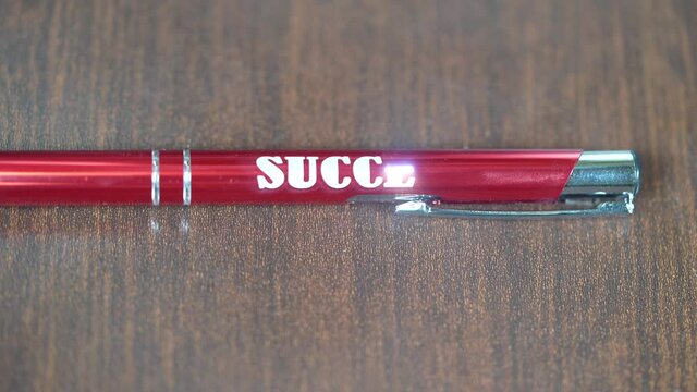 Laser engraving on metal red pen. Modern industrial technologies. Word Success