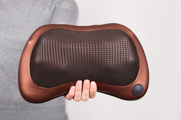 Hand with pillow for neck massage on grey background.