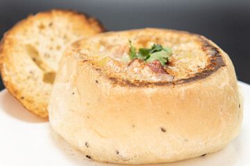 Bowl of hearty clam chowder contained in an oven baked bread bowl.
