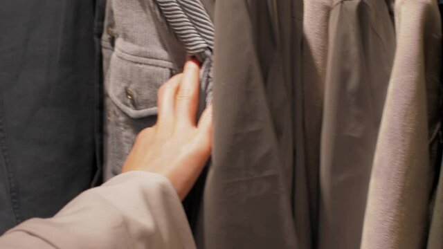 Experienced shopper hands touch different coloured warm jackets under electric light in department store. Concept winter season image
