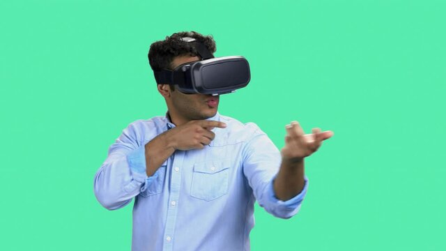 Young man wearing virtual reality glasses. Enthusiastic man with VR glasses simulating shooting with virtual gun on color background. Shooting VR game.