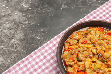 top view roasted eggplant salad in bowl on pink white checkered tablecloth on dark background with copy space