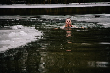 Fototapeta na wymiar Young slender girl bathes in winter in a river hole